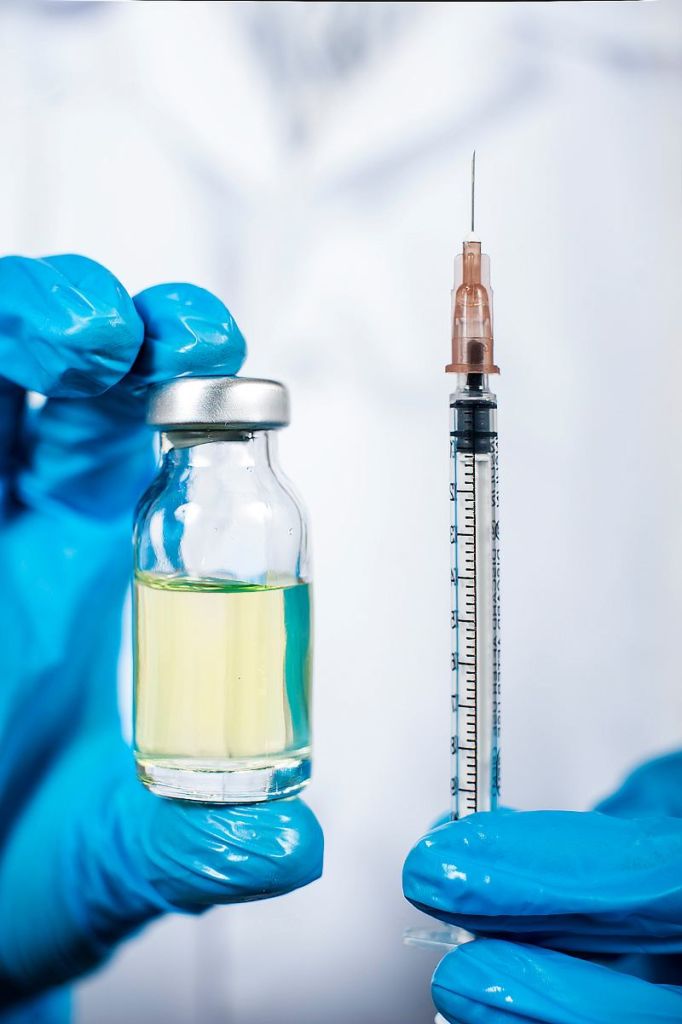 glass flask with a vaccine and a syringe in the hands of a doctor. close-up