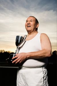 Middle-aged man on a weight loss journey Overweight middle-aged man wearing sports clothing holding a trophy
