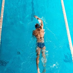 athletic swimmer in cap and goggles swimming in pool