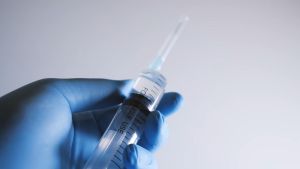 Gloved hand holding a syringe Gloved hand holding a syringe filled with CJC Peptide